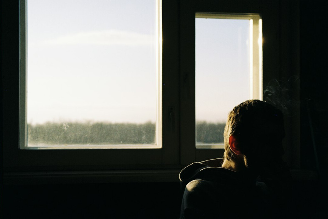 Person sitting calmly by a window in quiet reflection