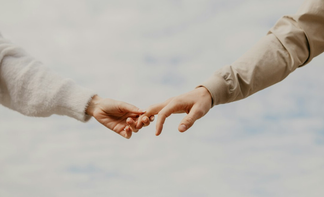 Two hands reaching out in a supportive handshake